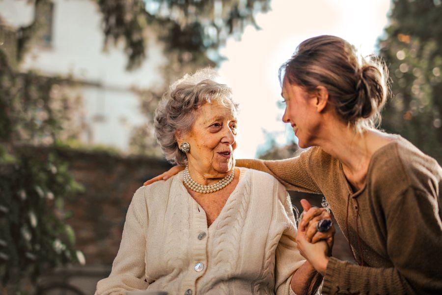 A care provider sharing a joyful moment with an elderly client outdoors